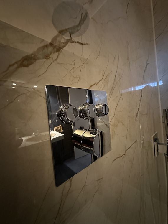 Inbouwthermostaatkraan in een wand met marmerlooktegels