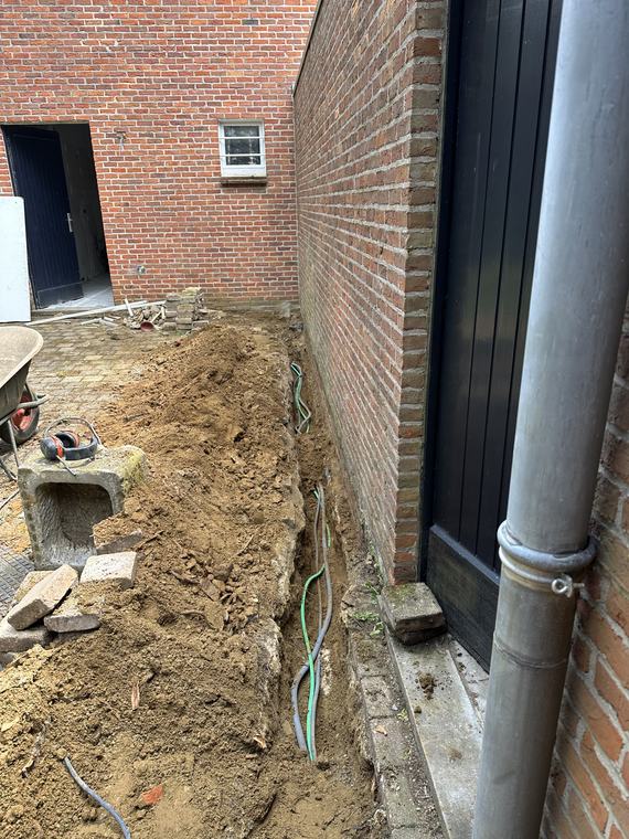 Grondwerken langs de gevel voor het aanleggen van nutsleidingen